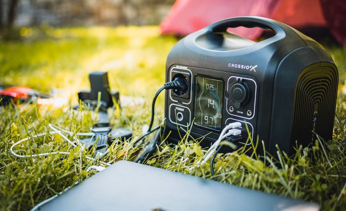 Bateriový generátor Crossio je položený na trávě a nabíjí notebook a další elektroniku